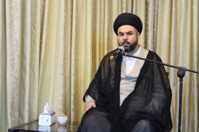 Hujjat al-Islam Sayyid Mohsen Mortazavi, in a black turban and cloak, speaking into a microphone.